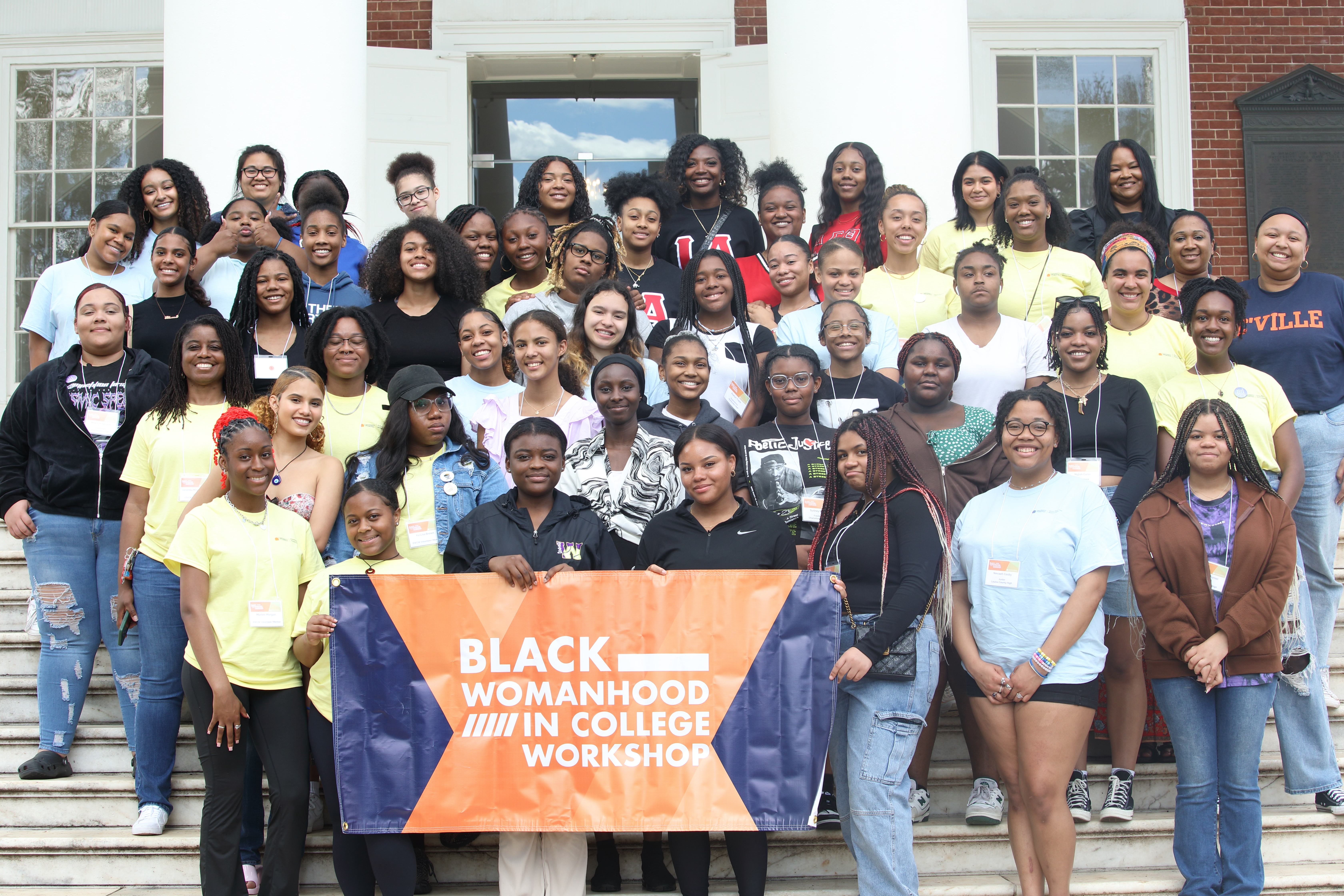 Group of women on rotunda steps holding banner that says "Black Womanhood in College Workshop"