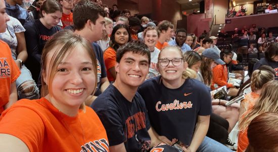Photo of students at UVA basketball game wearing UVA orange and blue merch 