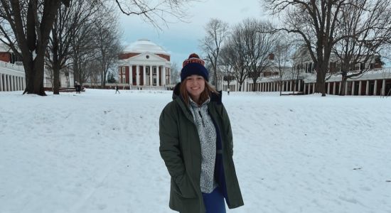 Leah standing on the lawn on a snowy day with the rotunda in the background