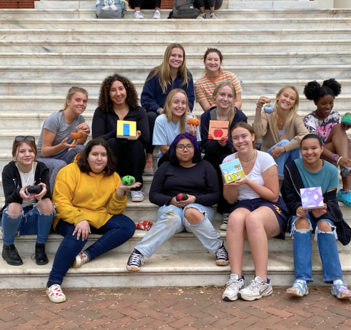 YWLP littles and bigs sitting on rotunda steps holding painted pumpkins
