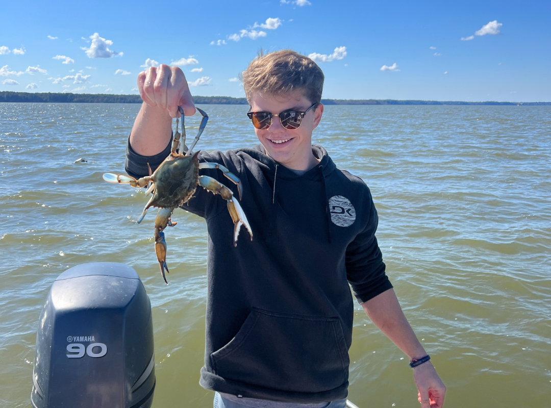 Ben on a boat holding up a crab 
