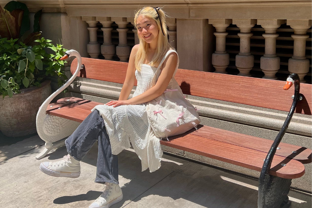 Photo of Jasmine in white dress and blue jeans sitting on a red wooden bench