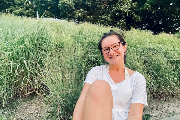 caitlin sitting and smiling in front of greenery