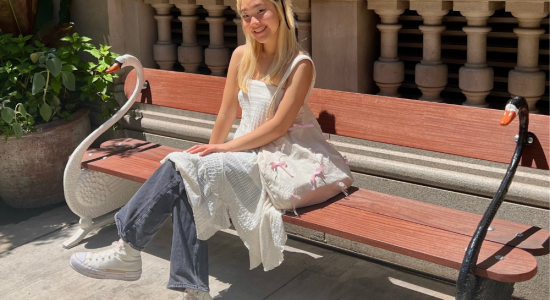 Photo of Jasmine in white dress and blue jeans sitting on a red wooden bench